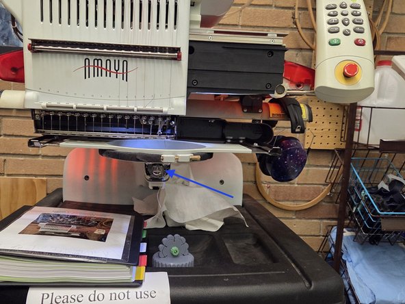 The bobbin is located under the hoop, and needs to be checked before embroidering. The Bobbin can be removed by pulling the release lever noted in the second image, towards you. The bobbin thread lasts 30,000 to 40,000 stitches, and may run out mid embroidery