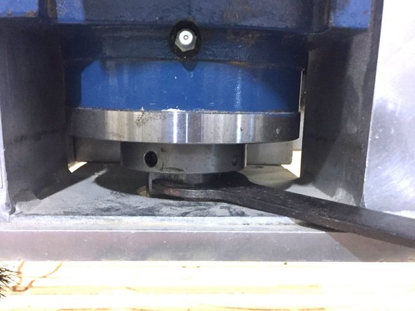 Insert the top wrench in the gap below the spindle mount.