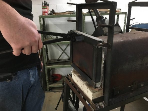 Using tongs, move front forge door to lowest pegs.