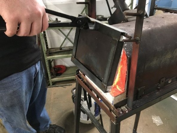 Using tongs, move front forge door to the top pegs