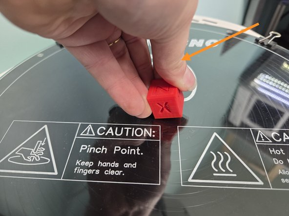 Your print will be attached to the glass build plate, and can be removed with either your hands like the second image, or a bed scraper if that isn't possible, like the third image.