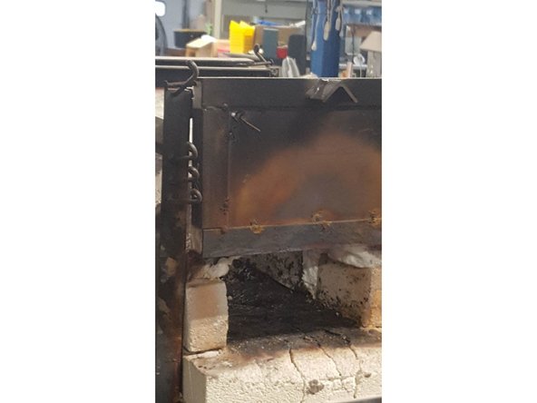 Place front forge door on top pegs.