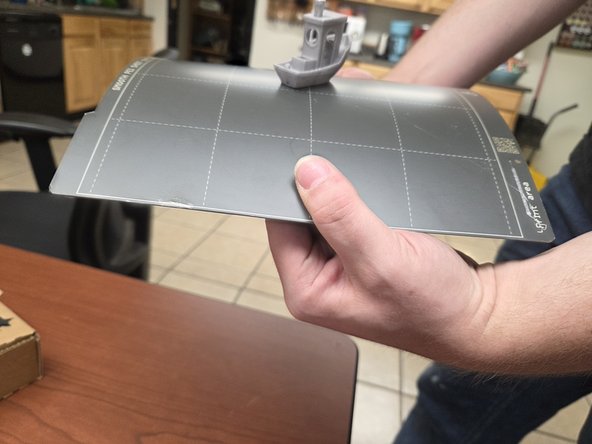 Most 3D prints will come off of the build plate with a little pressure, but if a print is being stubborn flexing the build plate like the third image will usually remove it.