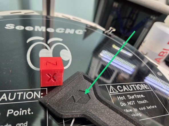 Your print will be attached to the glass build plate, and can be removed with either your hands like the second image, or a bed scraper if that isn't possible, like the third image.