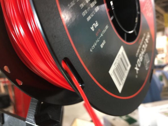 Use the holes on the side of the filament spool to secure the end and keep it from unspooling.