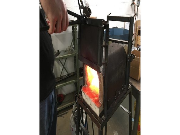 Using tongs, move front forge door to the top pegs