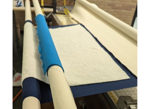 Pin quilt top to leader cloth on roller #2. Roll up, ensuring it is square and even.