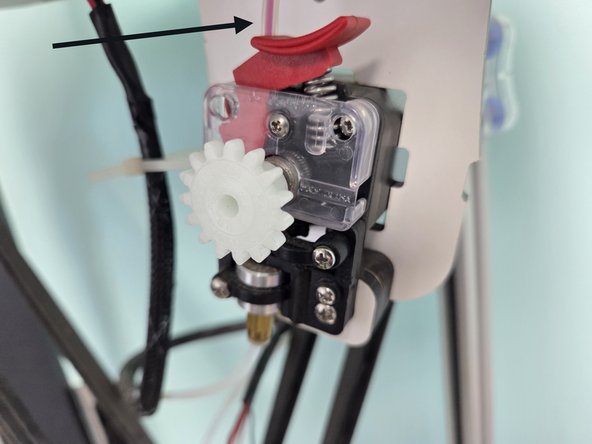 There is also a section of PTFE tubing hot glued to the top of the machine, feed the end of the filament through there so that it looks like the second image.