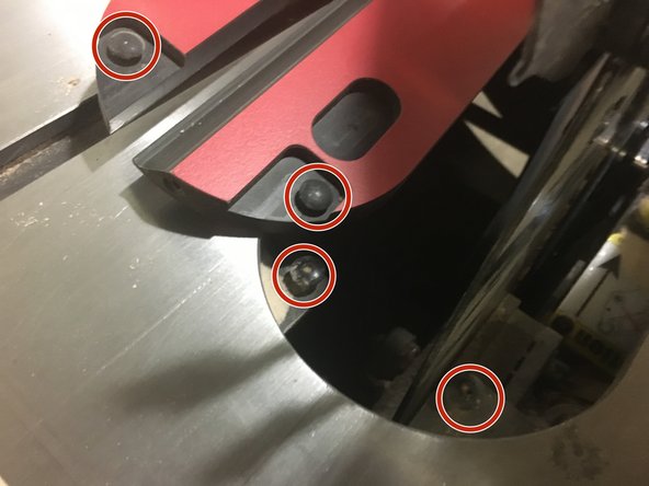 The backside of the throat plate engages under two pins that lock the back edge against the table.