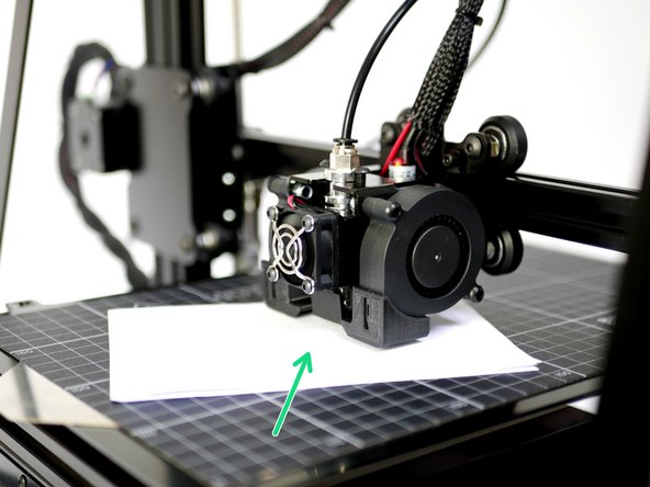 Take the folded piece of paper and place it between the surface and nozzle.