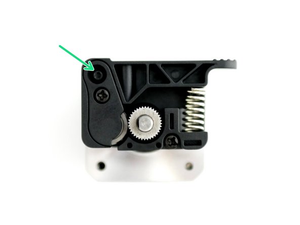 Compress the spring with the Idler Arm as shown in the second image.
