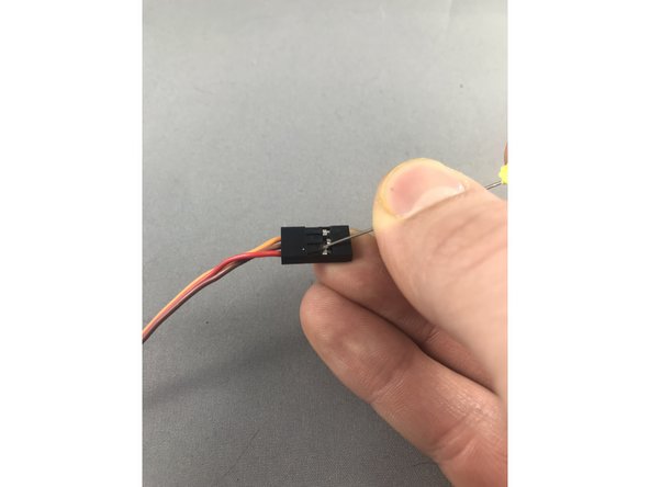 While gently pulling on the red wire, slide a sewing pin under the hook of the black JST header to carefully lift and release the crimp pin.  When you get it right the crimp pin will slide out.  Lifting too hard can break the hook so be gentle!