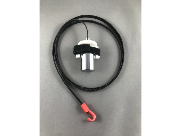 Prepare a 1m belt with the counterweight and insert it onto motor pulley. Try approaching the pinion gear sideways as shown in the picture for easy belt installation.