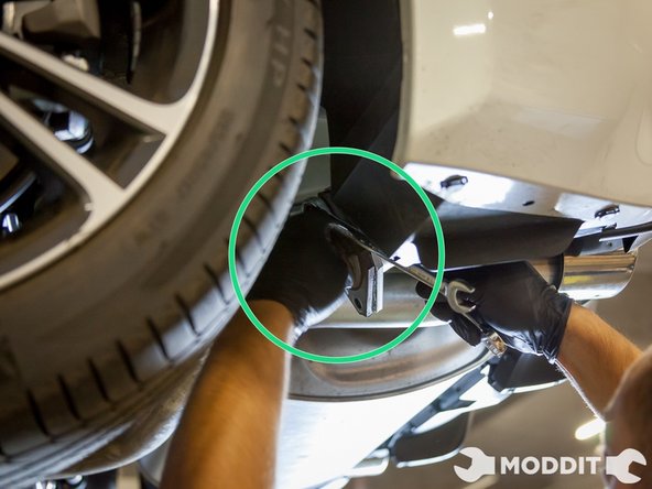 Go to the rear of the car behind the rear wheel to remove the bolts connecting the two sections of the exhaust.