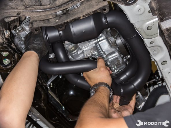 With your partner, hold the gasket to the flange of the header while lifting it up to mate with the engine. Once lined up and the studs are through the gasket and flange, you're ready to thread on the nuts.