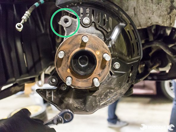 Using a 17 mm wrench, remove the two bolts securing the caliper to the knuckle.