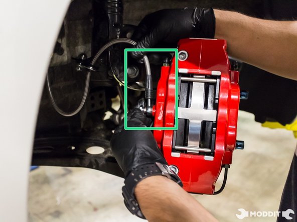 Using a 14 mm line wrench, secure banjo bolt to caliper with the stainless steel braided brake line positioning upwards.