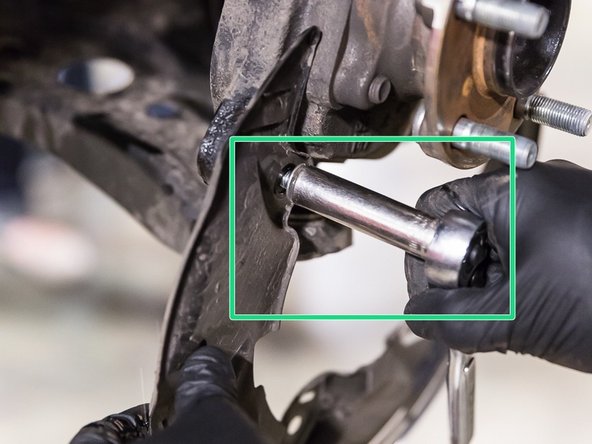 Using a 12 mm ratchet tool, remove the three bolts securing the dust shield to the knuckle.