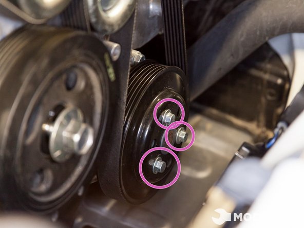 While the serpentine belt is still on the pulleys,  use a 10mm socket with a ratchet to loosen the water pump pulley.