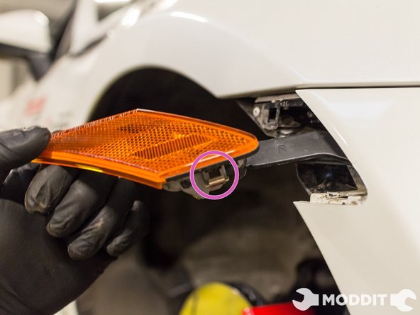 On each side of the vehicle's front wheel well, remove the side markers. They are held in place by metal compression clips.