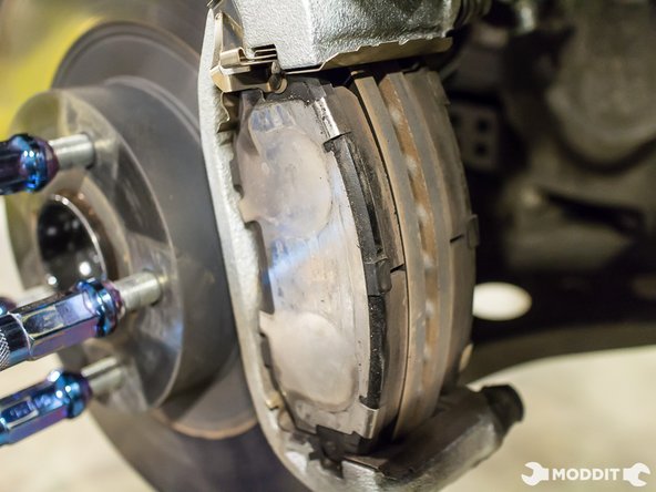 After removing the caliper, securely support it so it does not add stress to the brake line.