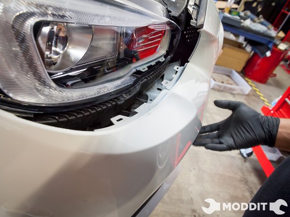 Starting from the sides of the bumper, carefully pull them out to free from the fender.