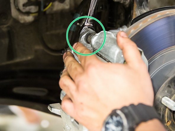 With a 14 mm wrench, remove the upper and lower bolt securing caliper to caliper bracket.