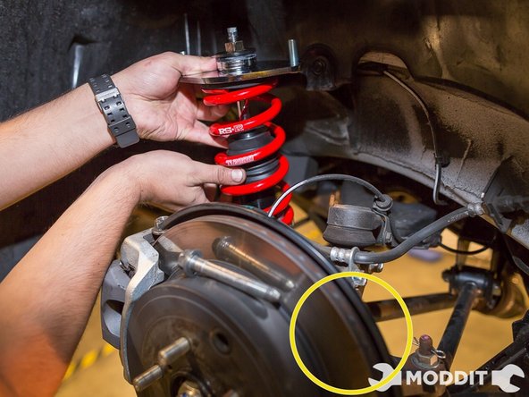 We started off in the rear as it is a direct bolt in. First thing you do is you take the rear coilover and angle it into the slot of the control arm.