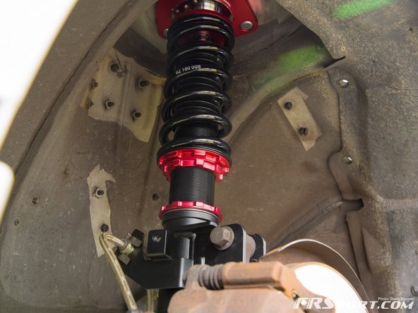 Align the bottom of the coilover up with the spindle and use some force to hold it up and align the holes.