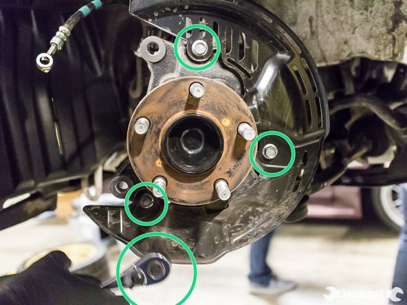 Using a 12 mm ratchet tool, remove the three bolts securing the dust shield to the knuckle.