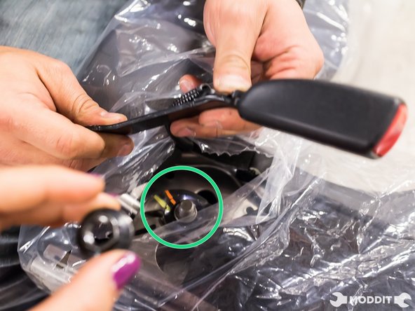 With the 14mm wrench or ratchet, remove the factory seatbelt buckle.