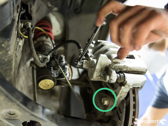 Using a 17 mm wrench, remove the two bolts securing the caliper to the knuckle.