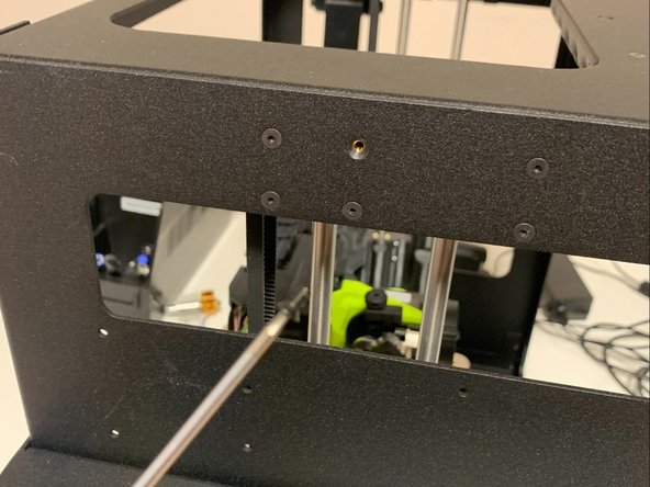 Using the provided longer flat head M3 x 7 mm screw from this adaptor kit, mount the plate to the side of the printer as shown. Tighten the screw ensuring that the plate is level.