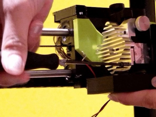 Re-install the cooling fan assembly with bottom left and bottom right bolt of heat sink. Start with bottom-right to secure cooling assembly. Press it upwards against the hot end assembly. Screw in bottom-left to also secure the cooling assembly. Nextscrew top-left with the red wire, using the shortest of the our screws.