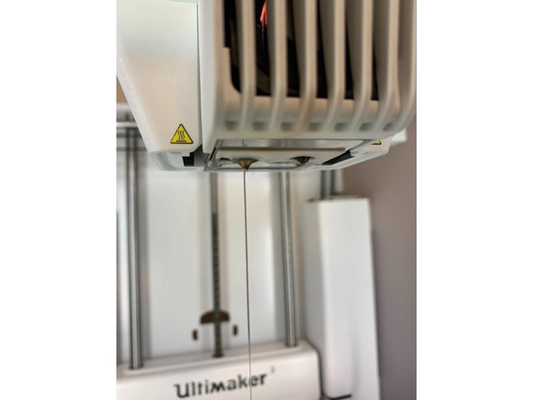 Find 20-30cm of clear or white PLA. Manually load into the print core from the top of the print head until you have purged any remaining material which was in the print head. You should only see clear filament coming from the nozzle when it has been fully purged. Pull the filament you just inserted back out before proceeding to the next step.