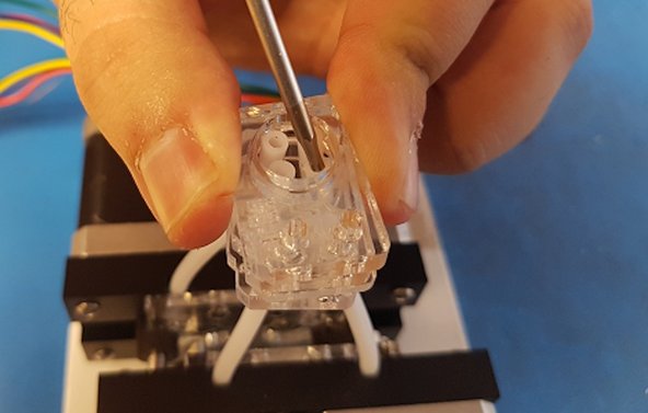 Stack the M2 plate in a similar position, and then place the M1 plate on top. You'll notice that the middle hole in the M1 plate is smaller than the other acrylic plates. You'll need to use a tool (such as a screwdriver) to help you carefully wedge the tubes together to fit.