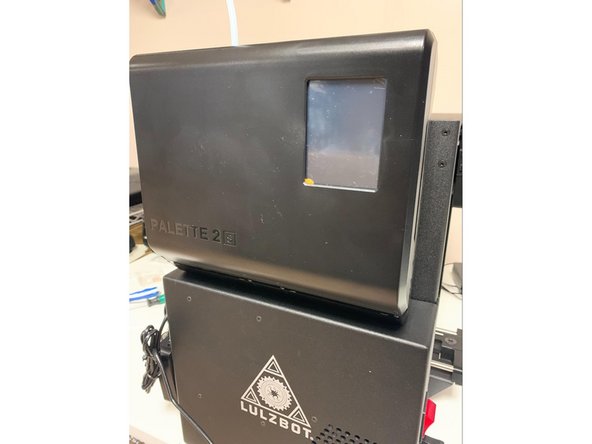 Slide Palette onto the mount and ensure that it is secure before allowing it to stay on its own. The bottom of Palette will rest on the top of the electronics enclosure on the side of the printer. Be cautious when working with Palette or when moving the printer while Palette is installed as Palette will separate from the printer if lifted upwards. 