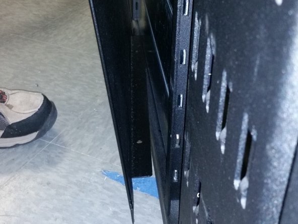 Place the bent flange of the side panel onto the base of the rack and rotate the panel into position until all (4) screw wholes in the panel are aligned to the holes in the rack.