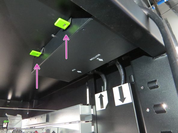 To release the AC PDU, pull down on the two green tabs as shown.