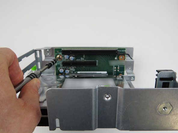 Remove (2) phillips head screws which secure the riser card to the cage.