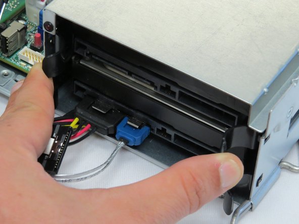 Squeeze the two retention tabs on either side of the HDD.