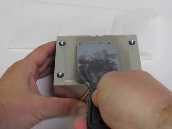 Scrape the thermal compound parallel to the machined grain, as shown.