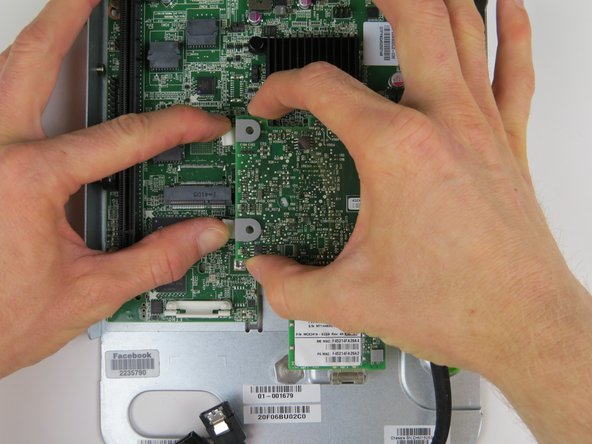 To release the NIC, carefully press down on the retention tabs as shown.