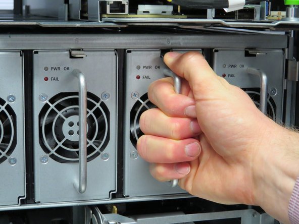 Press the retention tab down and pull the power supply outwards to remove it.