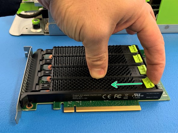 Remove the NVMe metal cover by first pulling green tab towards the center of the AVA card and lifting up.