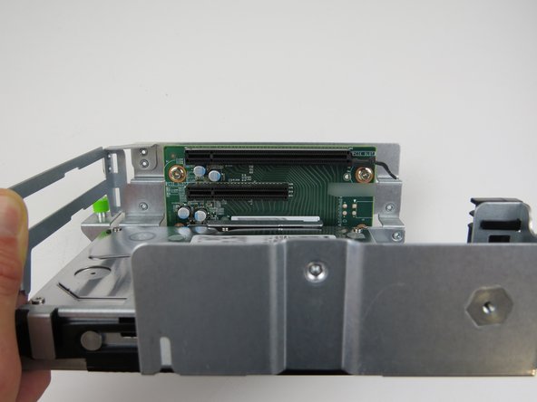 Remove (2) phillips head screws which secure the riser card to the cage.