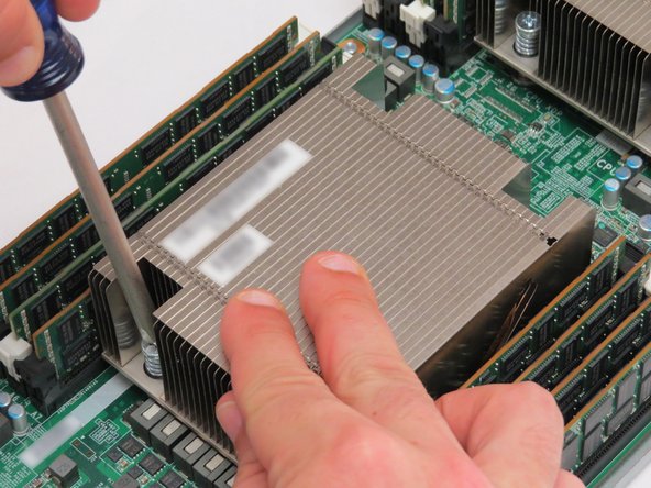 Lightly press the heatsink downwards next to the screw being loosened.