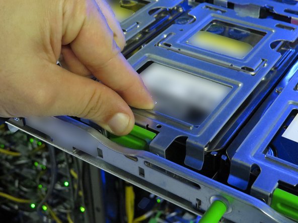 Press the green tab on the HDD tray gate containing the failed HDD.