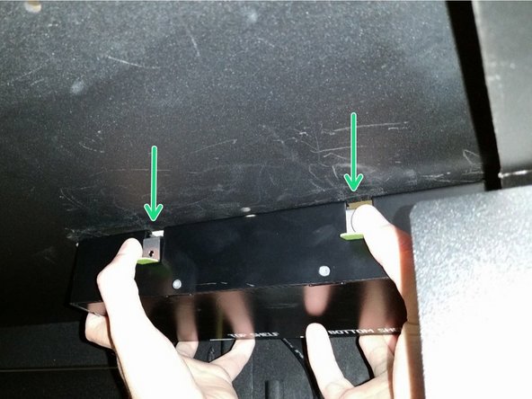 While pulling down on the two green tabs on the PDU, pull the PDU towards the center of the rack until the PDU is free of the roof and is able to hang downward.