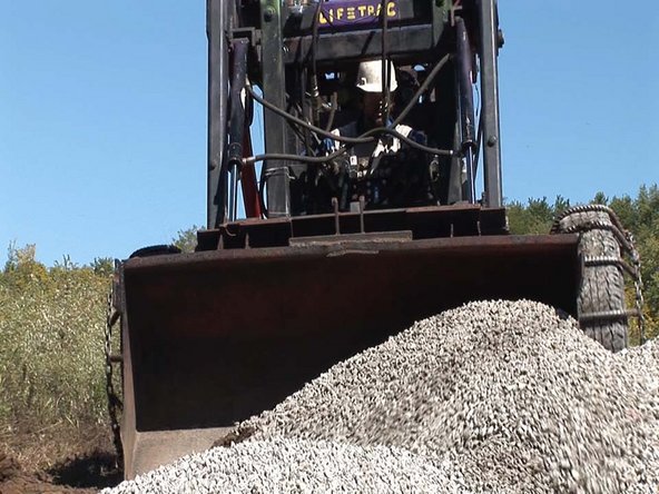 You can strip off the topsoil, as well, or otherwise change the grade at this point. In our case, we had little topsoil and we liked the way the grade worked out by raising the building up on the gravel.